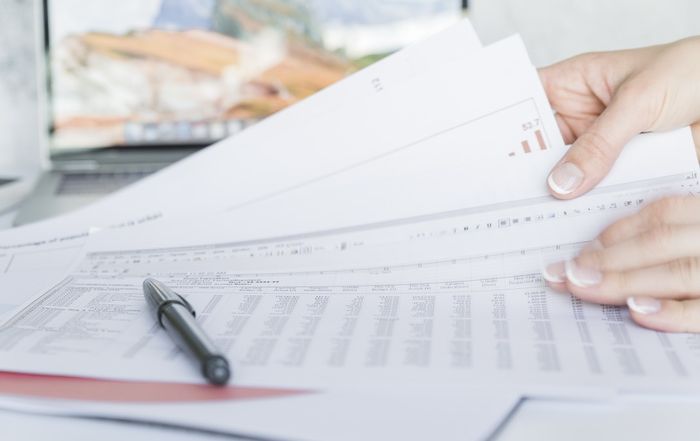 hands holding papers with data on desk resize